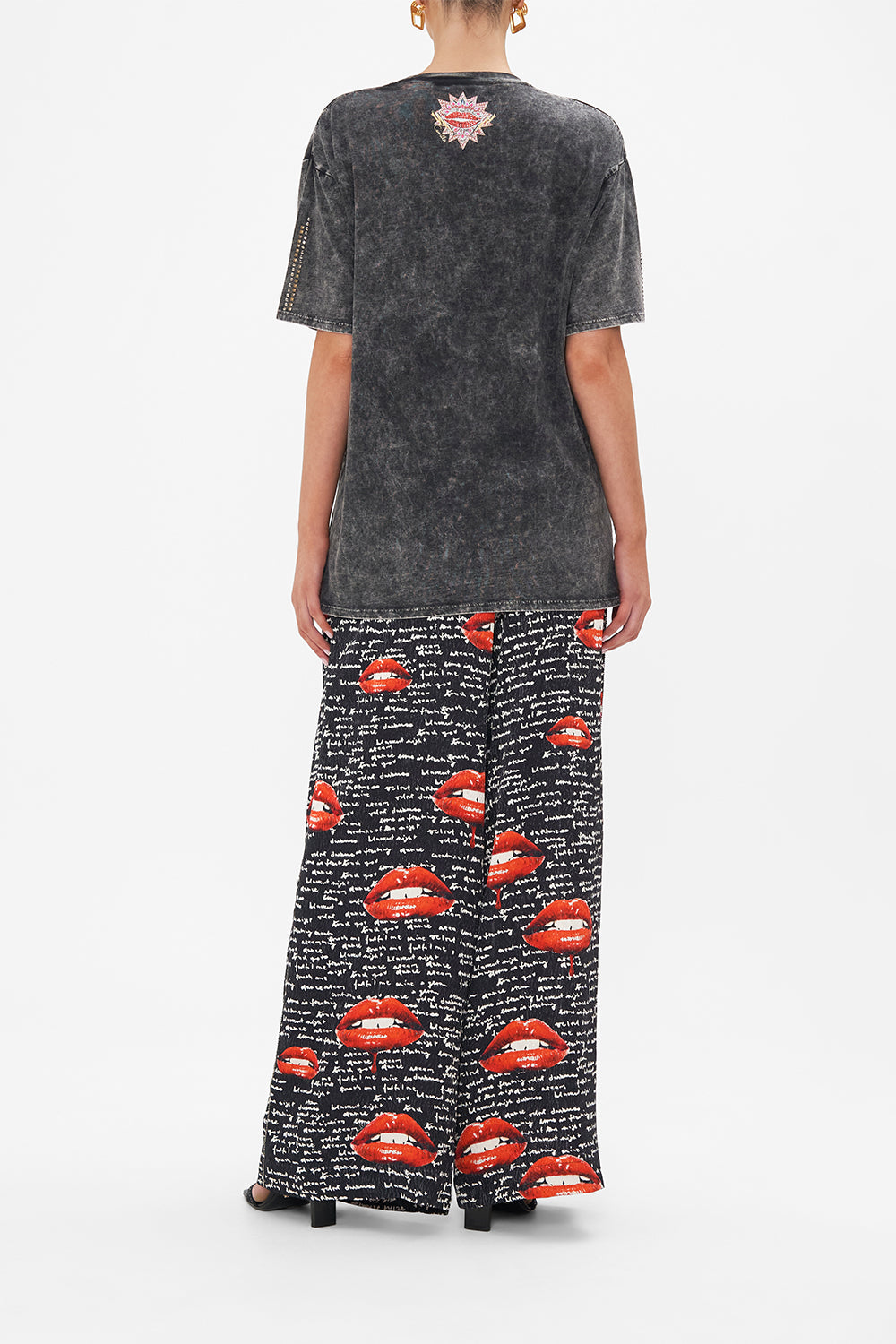 Back view of model wearing CAMILLA black acid wash graphic tee in Chaos Magic print