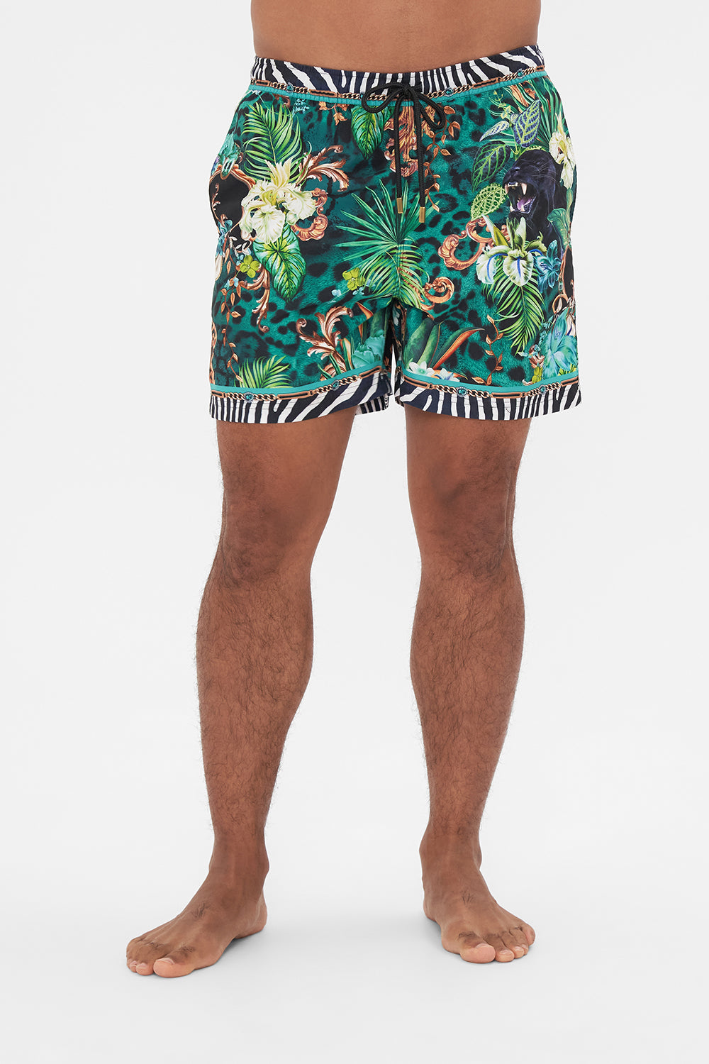 Crop view of model wearing Hotel Franks by CAMILLA mens green boardshorts in Sing my Song print