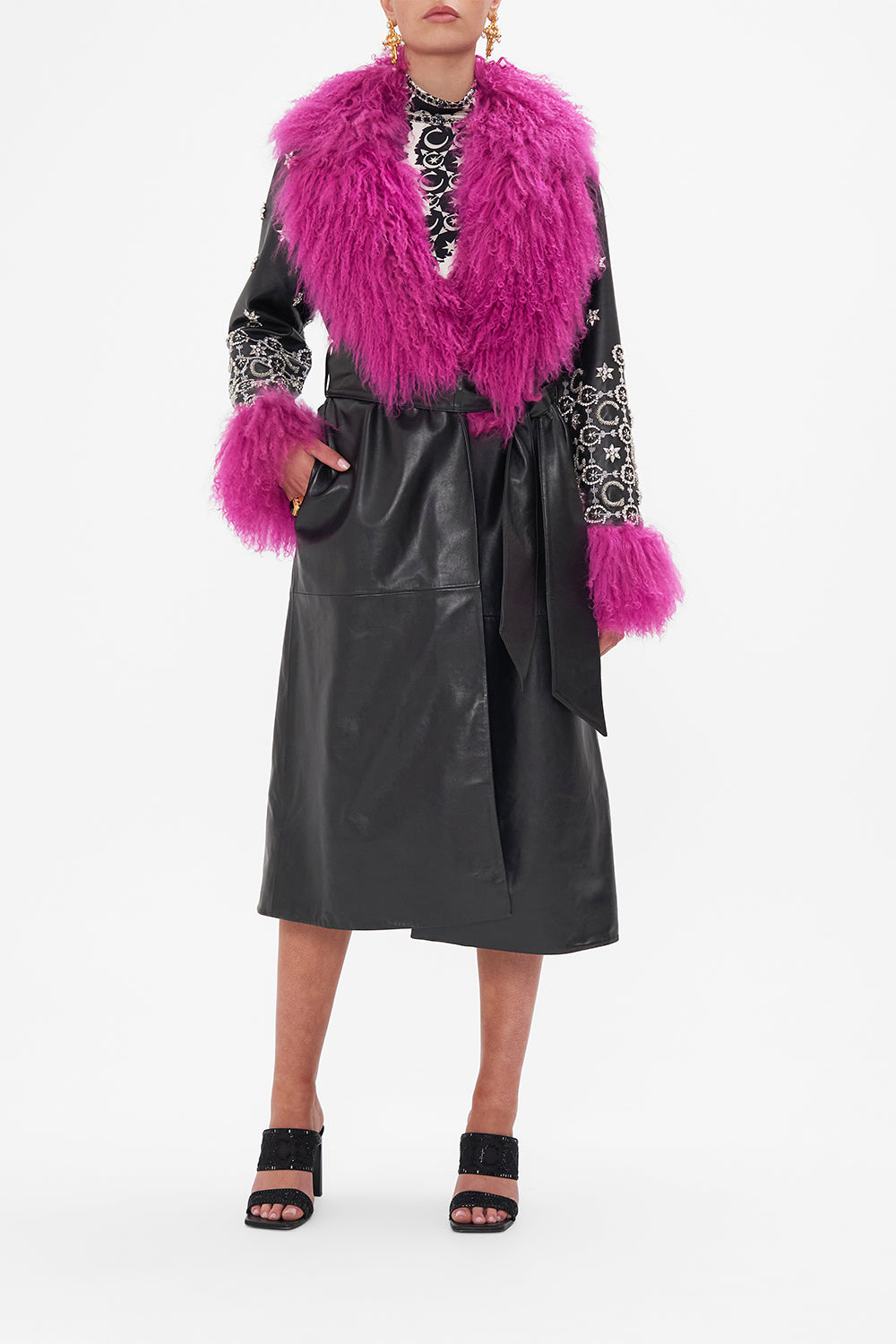 Front view of model wearing CAMILLA black leather trench with fur cuffs and collar