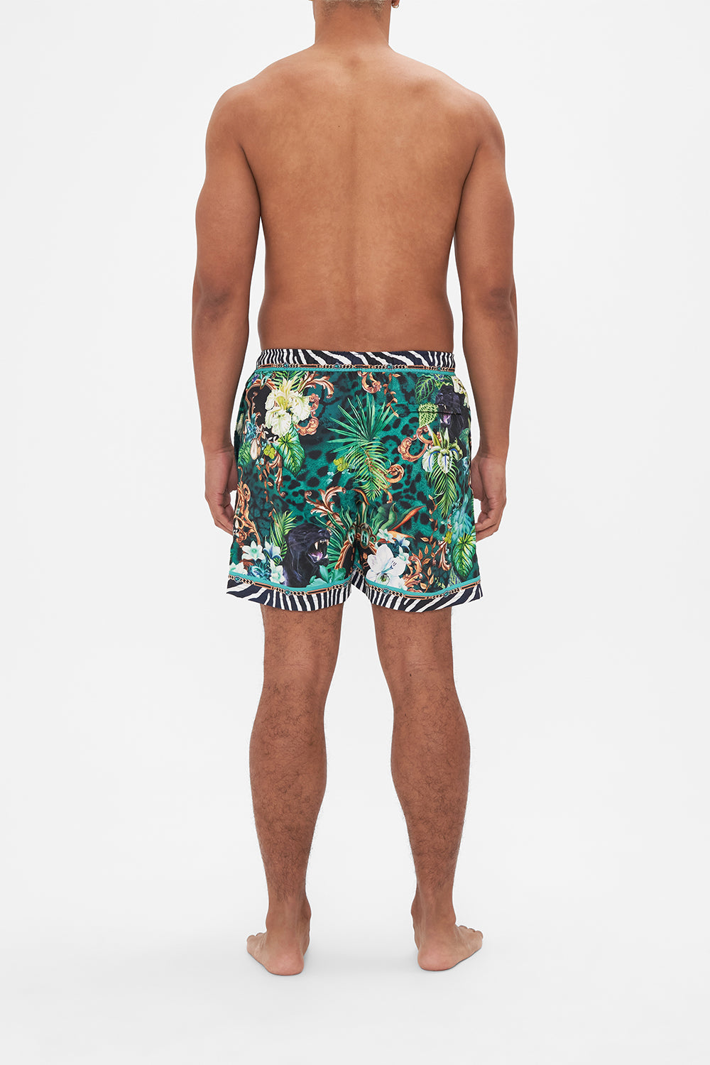 Back view of model wearing Hotel Franks by CAMILLA mens green boardshorts in Sing my Song print