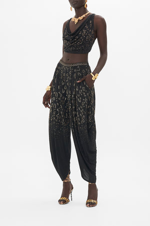 Side view of model wearing CAMILLA black jersey pants in Mosaic Muse print