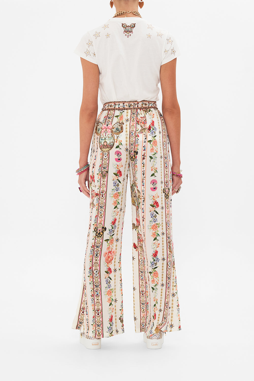 Back view of model wearing Disney x CAMILLA silk pants in Minnie Magic Forever print
