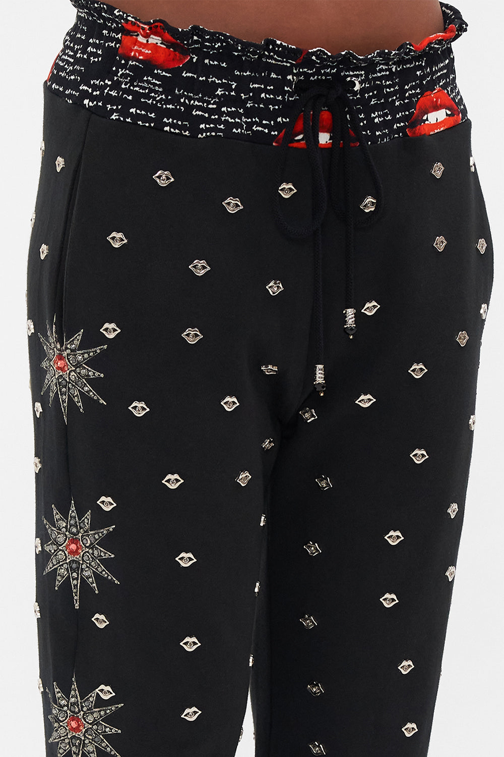 Detail view of model wearing CAMILLA black trackpants in Chaos Magic print