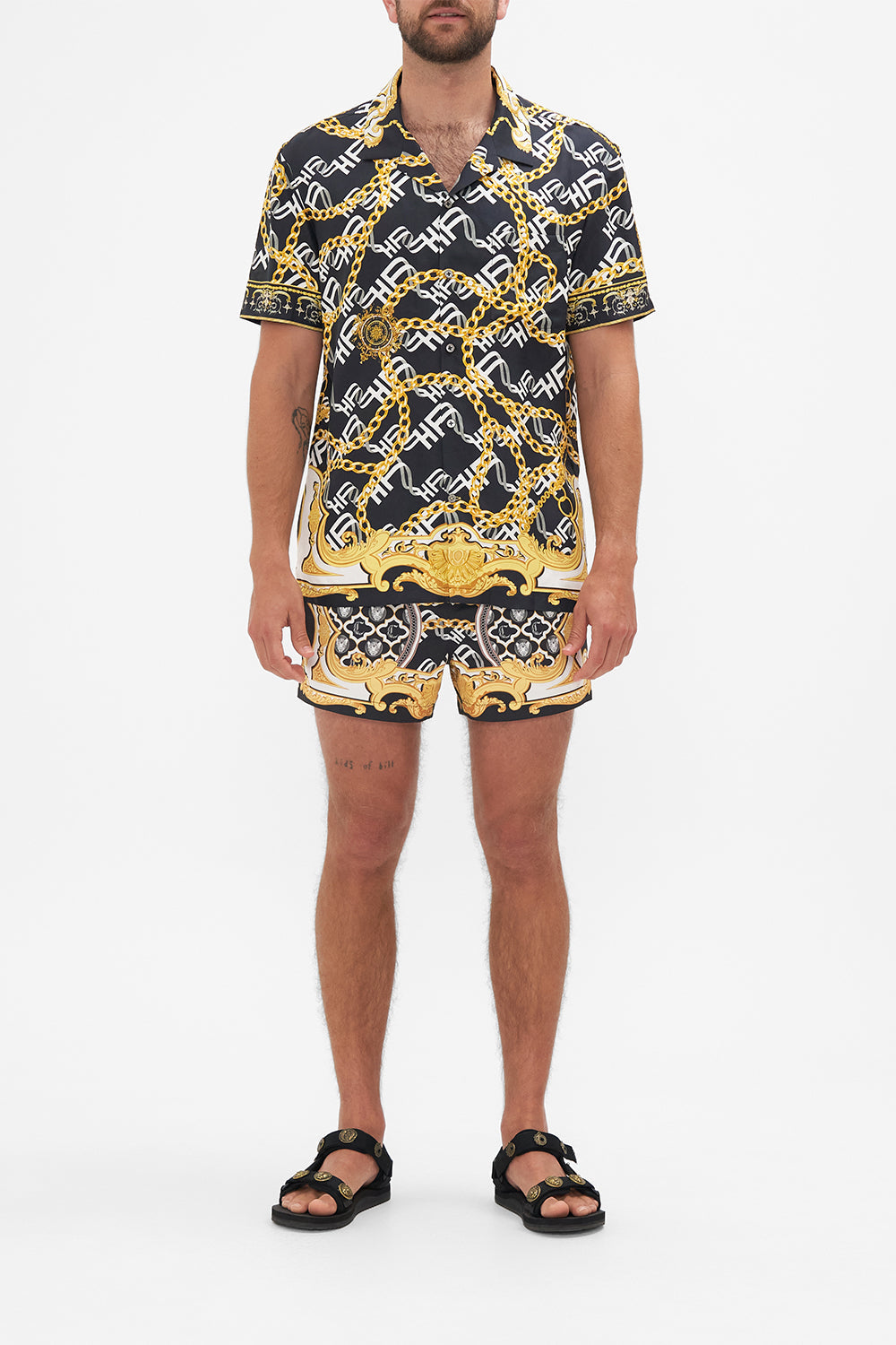 Front view of model wearing Hotel Franks by CAMILLA silk mens short sleeve camp collared shirt in black and gold Tether Me Not print